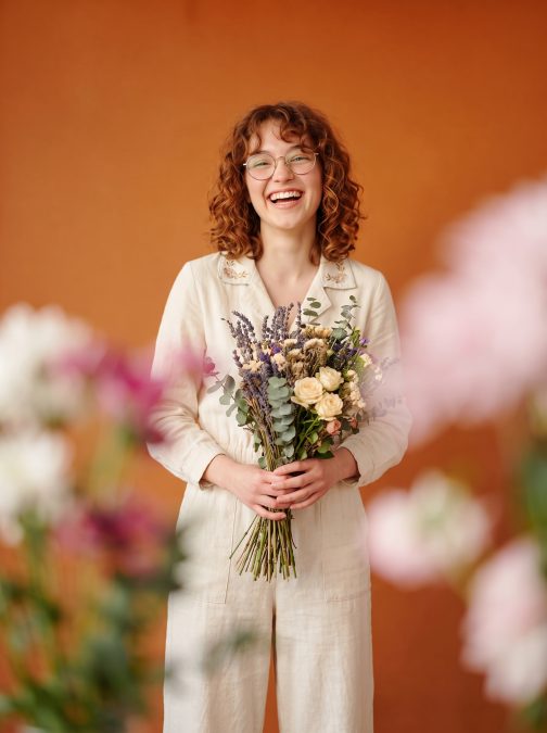 Client holding a spring bouquet in front of an orange studio backdrop