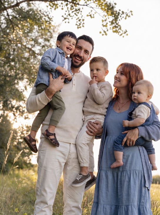 Family of five with three young children photographed outdoors at golden hour